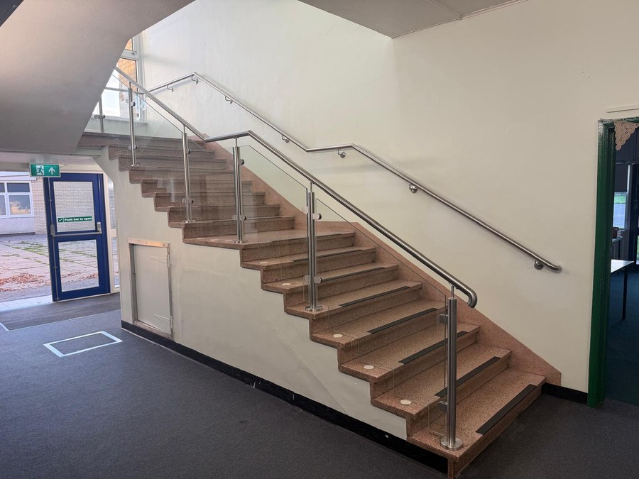 Stainless steel and glass balustrade with shaped glass panels to a terrazzo school staircase in York